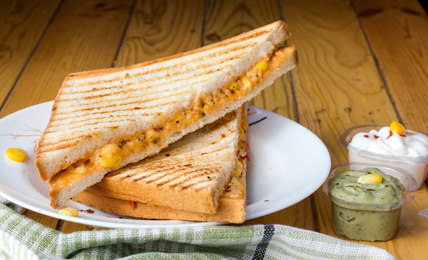 Toasted sandwich stacked with chicken and avocado, cut in half on a plate