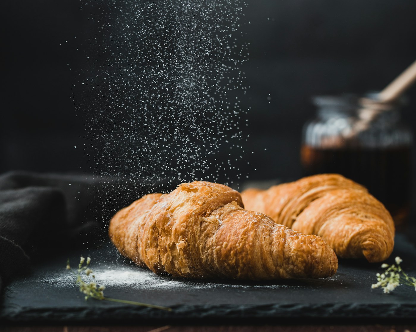 Two golden butter croissants dusted with icing sugar